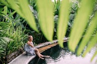 Woman Sitting with Her Feet in Water in a Tropical Pool Among Plants