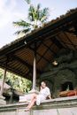 Woman in Robe Resting on Patio Under Straw Roof