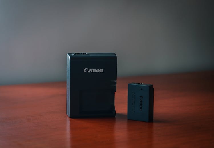 A Battery And A Charger On A Wooden Surface