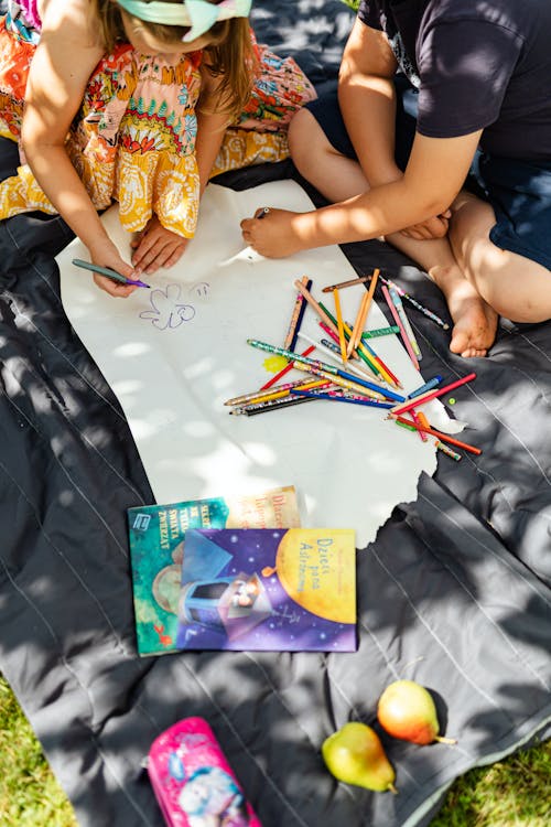 Free Kids Sitting on the Picnic Blanket Writing on Paper Stock Photo