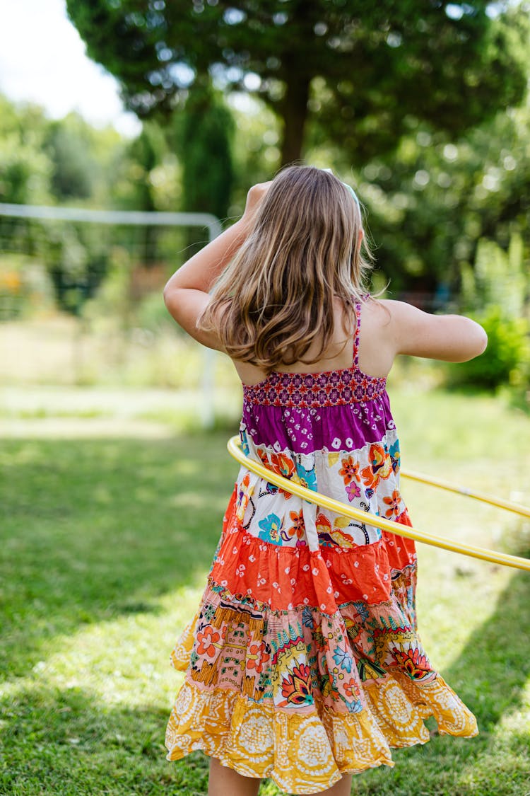 A Girl Playing Hula Hoop On The Green Grass