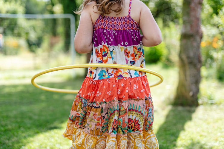 A Girl In Floral Dress Playing Hula Hoop