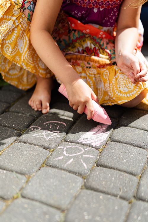 Free Young girl drawing with pink chalk on outdoor pavement in sunny weather. Stock Photo