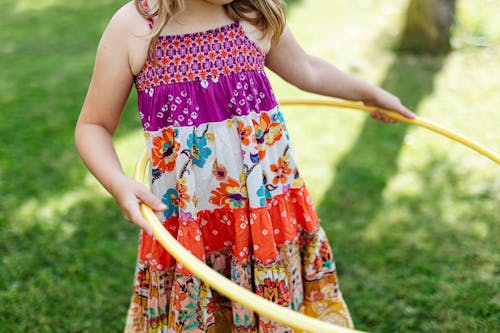 Child in Floral Spaghetti Strap Dress Holding Yellow Hula hoop