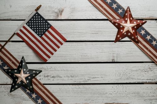 Free Overhead view of national flag of America between decorative ribbons with stars and stripes on wooden surface Stock Photo
