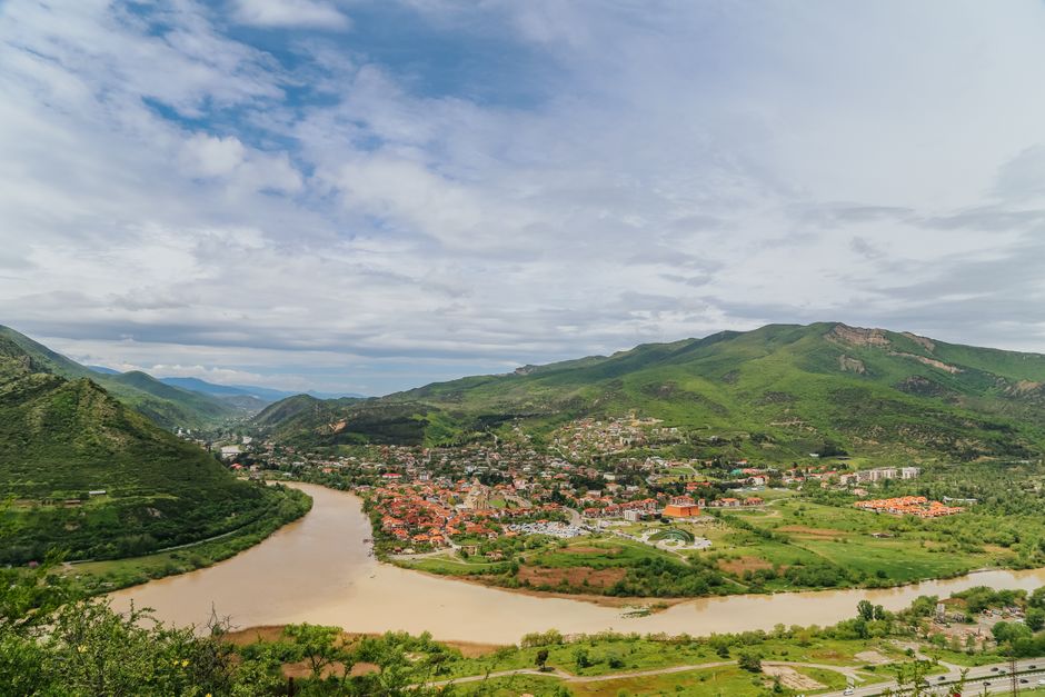 Vue aérienne pittoresque de Mtskheta, en Géorgie, avec des montagnes verdoyantes et une rivière, mettant en valeur la beauté naturelle.