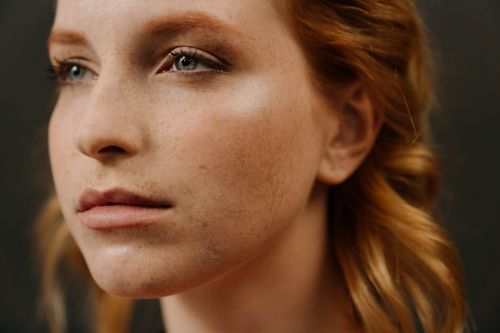 Free Close-up portrait of a freckled redhead woman with captivating eyes against a black background. Stock Photo