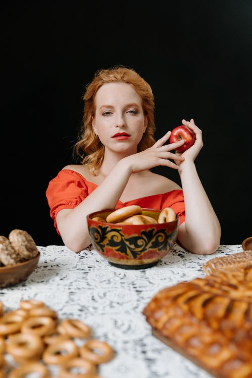 Free Redhead woman in traditional dress with Russian sweets and apple. Stock Photo