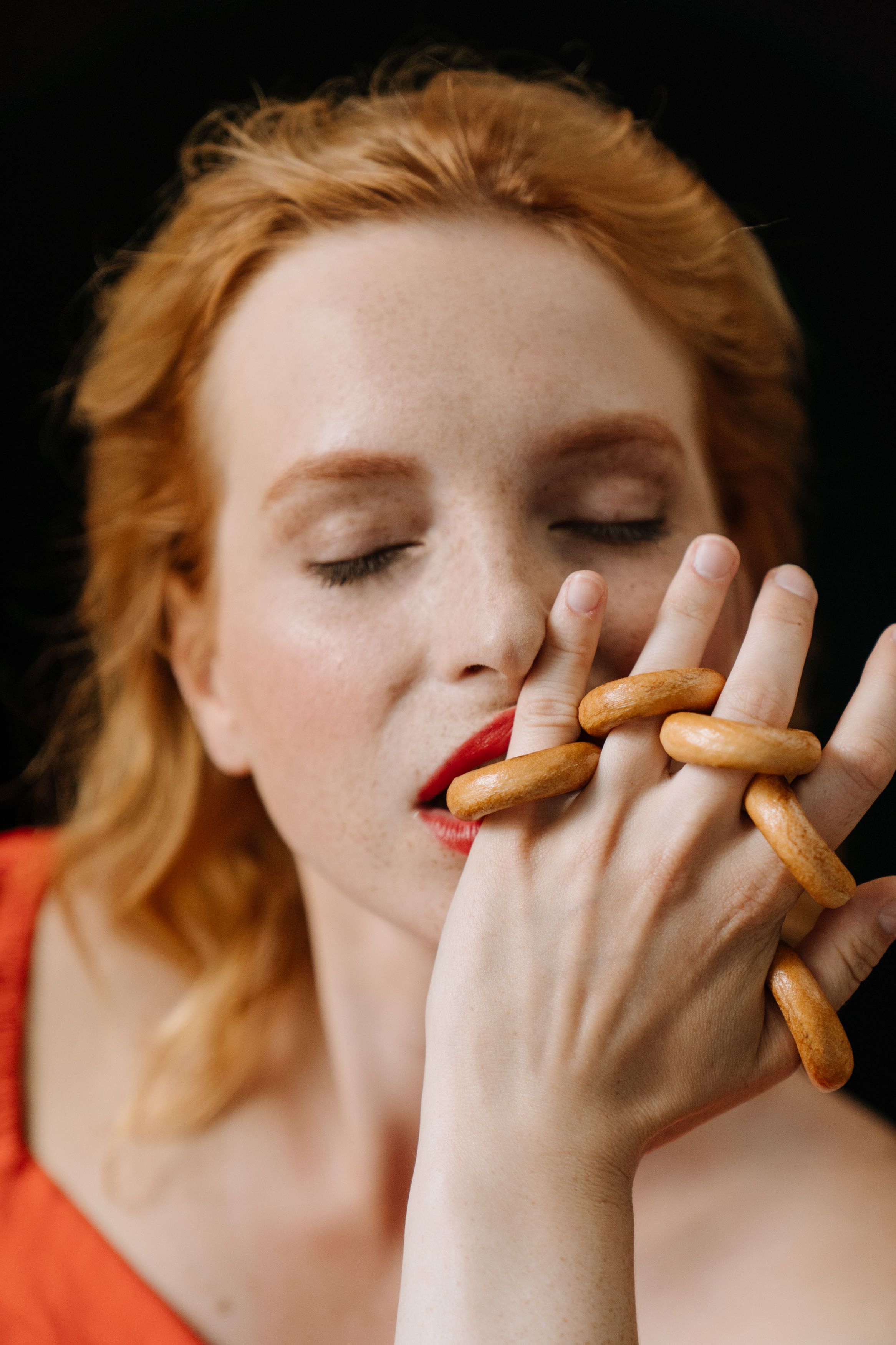 Redhead woman savoring traditional Russian sushki in an intimate close-up portrait.