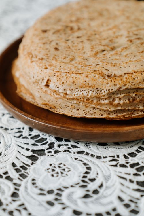 Free Close-up of traditional Russian blini on a wooden plate atop lace tablecloth. Stock Photo