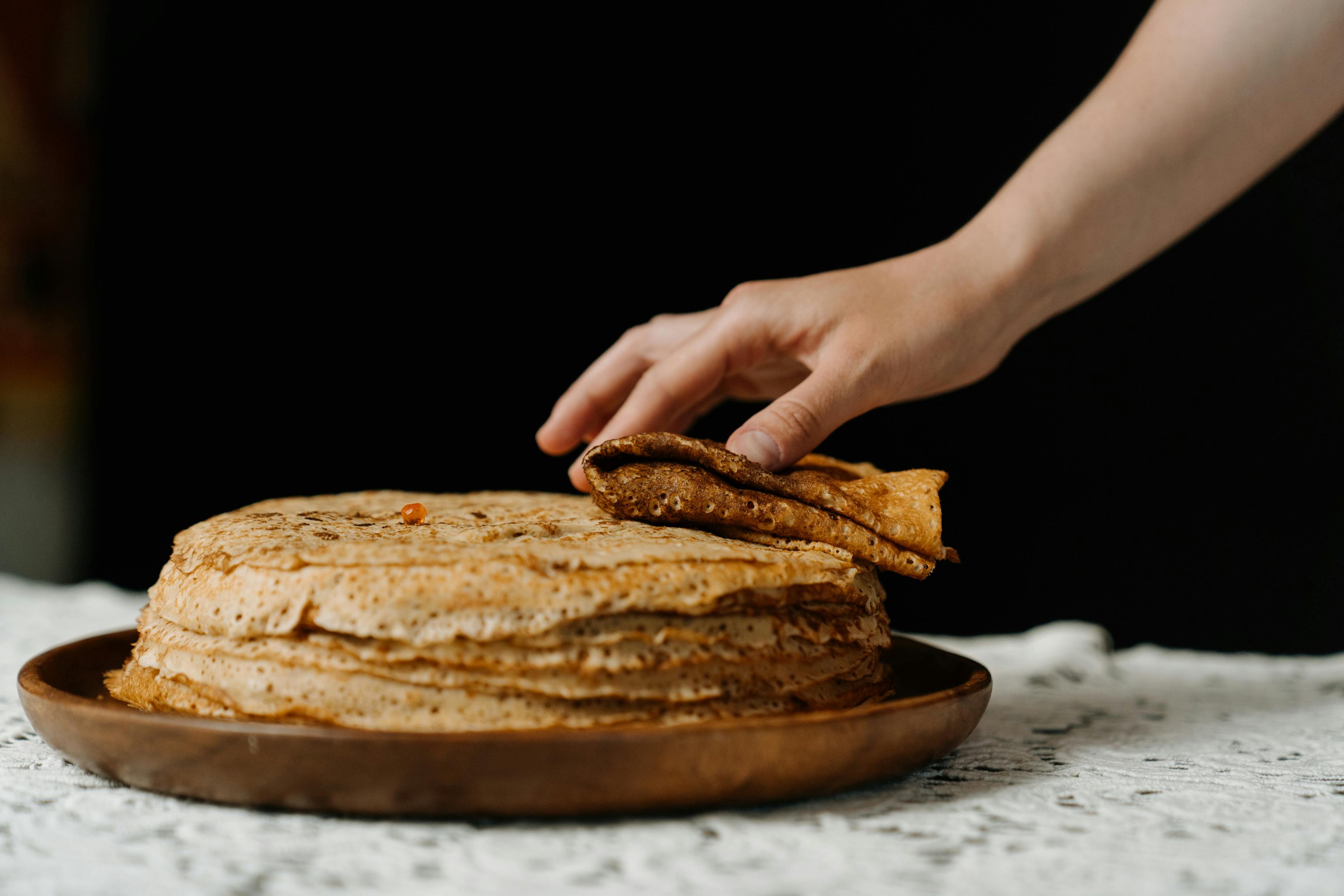 person holding brown bread on brown wooden round plate