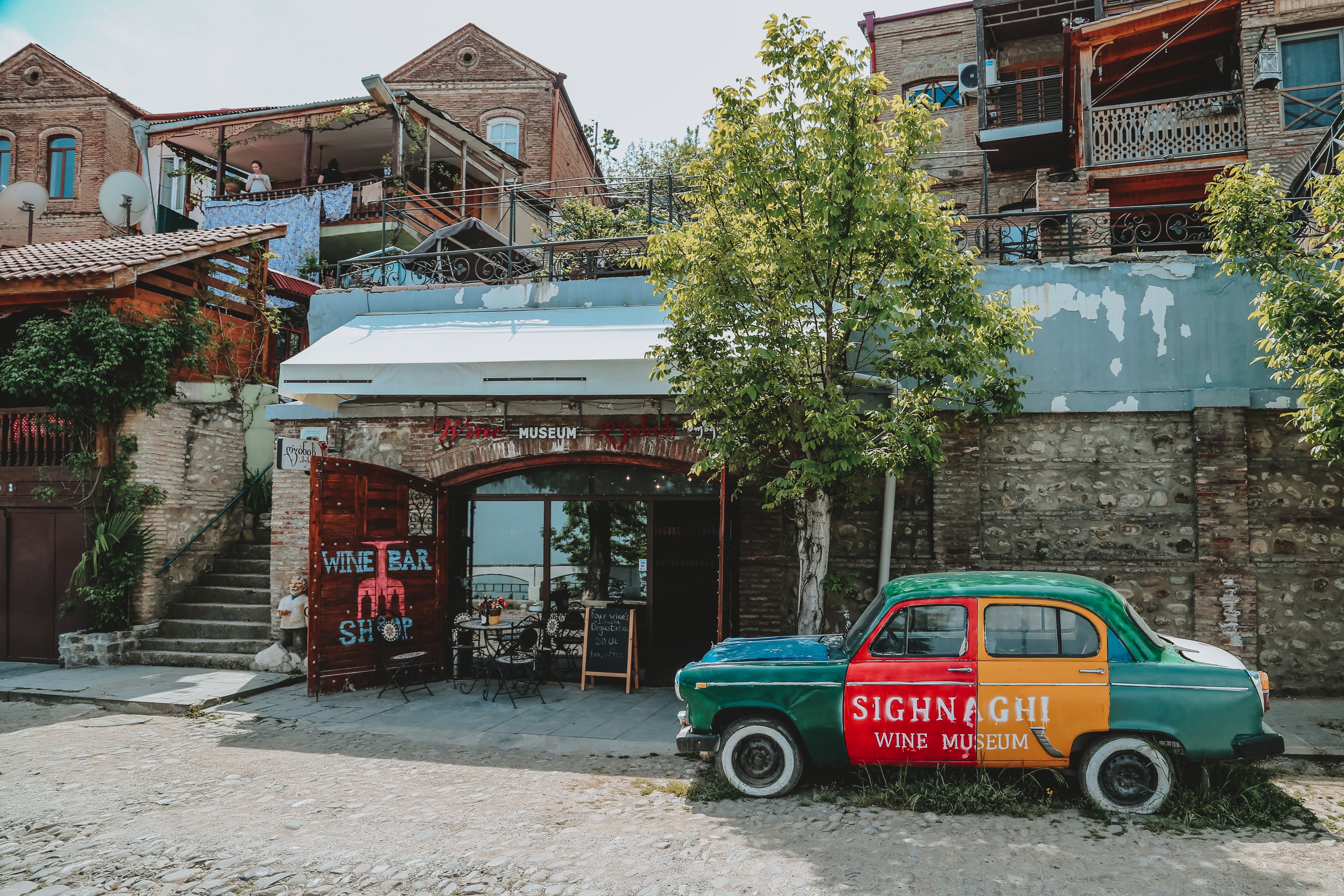 Exterior of aged stone buildings with vintage car parked near restaurant in sunny day Exterior of aged stone buildings with vintage car parked near restaurant in sunny day