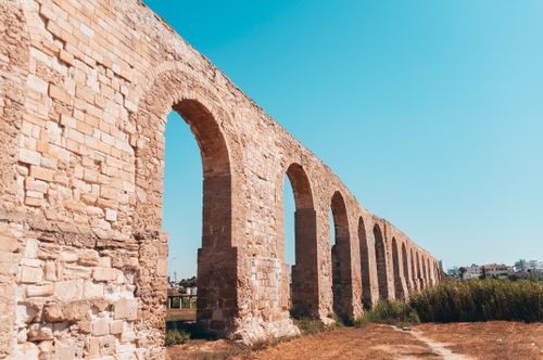 Free A beautiful historic stone aqueduct under a clear blue sky in a sunny outdoor setting. Stock Photo