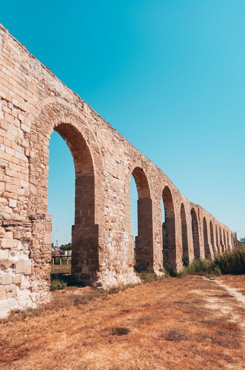 Free A well-preserved Roman aqueduct under a bright blue sky, showcasing ancient architectural beauty. Stock Photo