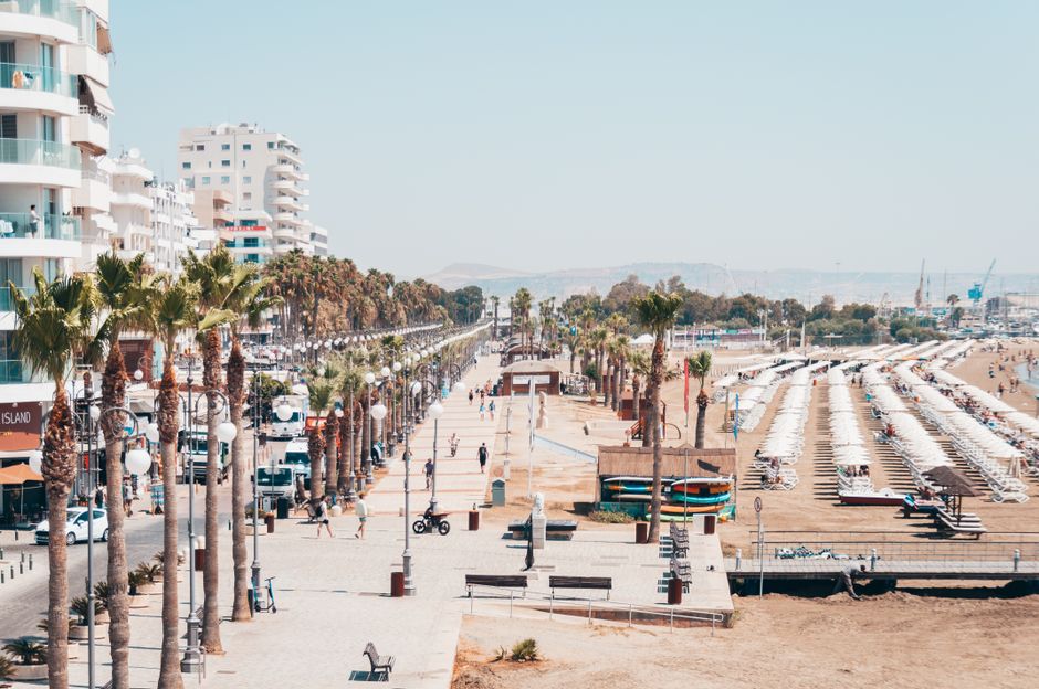Larnaca seafront promenade with palm trees and beach, illustrating the coastal Cyprus context for rising damp risk.