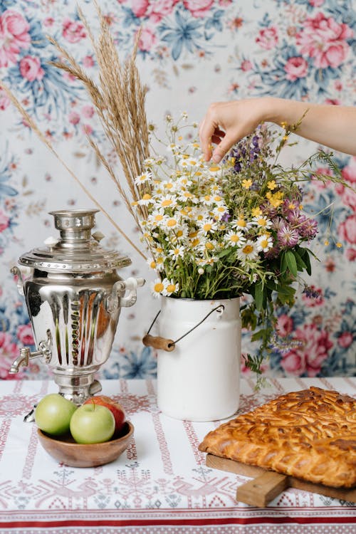 Person Holding White and Yellow Flowers in Vase