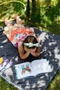 Girl Reading Book on Blanket