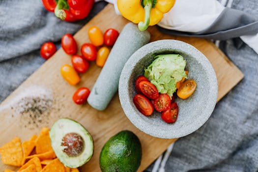 Colorful assortment of fresh vegetables and ingredients for guacamole, artfully arranged.