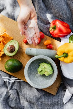 Top view of fresh guacamole preparation on a cutting board with avocados, peppers, and chips, capturing healthy eating.