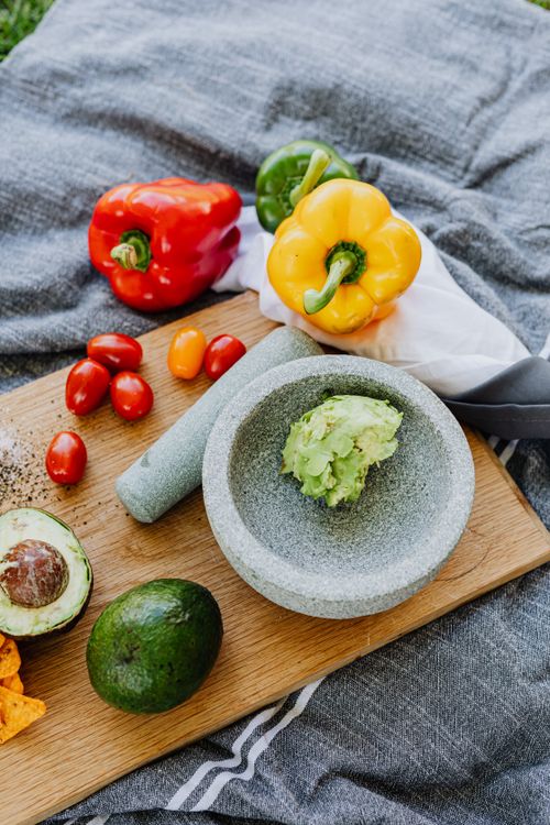 Free A vibrant display of fresh vegetables including avocados, peppers, and tomatoes with a mortar and pestle. Stock Photo