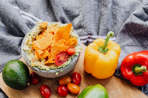 Guacamole with Nachos and Tomatoes Beside Fresh Vegetables