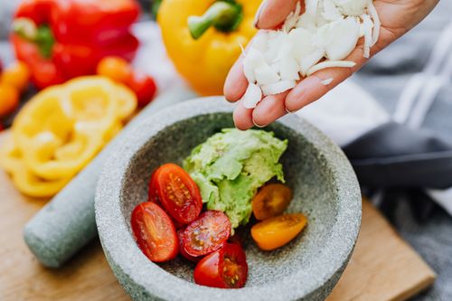 Free Colorful ingredients like avocados, tomatoes, and onions in a stone mortar for guacamole. Stock Photo
