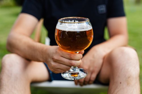 Free A man holding a glass of beer in an outdoor setting during the day. Stock Photo