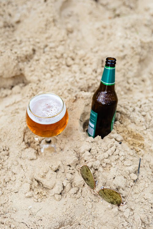 Free Beer and Sunglasses on the Sand Stock Photo