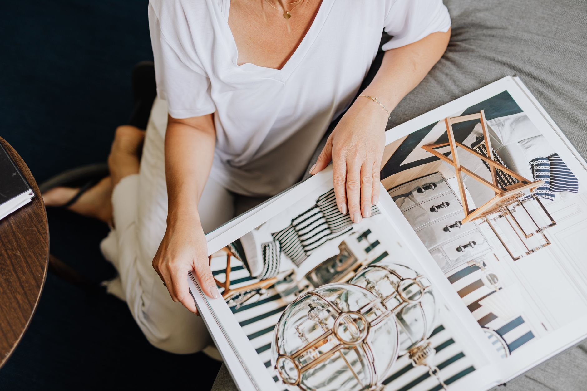 Casually dressed woman flipping through a modern interior design magazine at home.