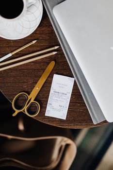 Flat lay of coffee cup, laptop, and office supplies on wooden table, ideal for business stock imagery.