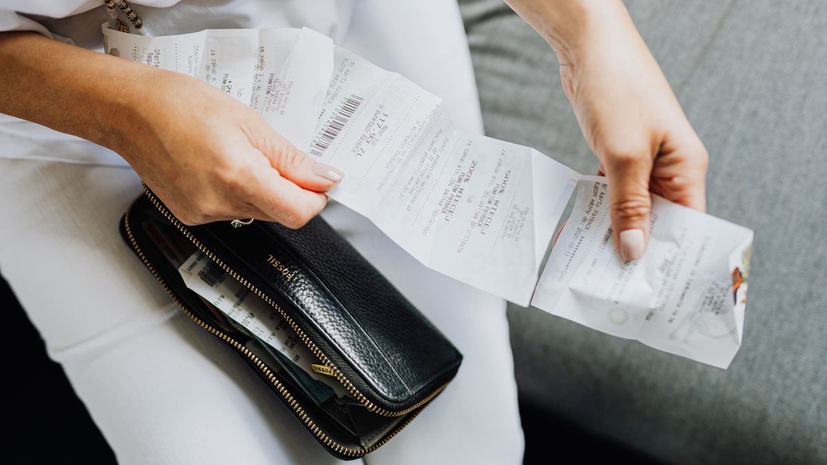 Close-up of a woman's hands managing multiple receipts taken from a black wallet.
