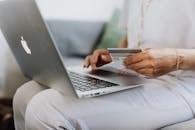 Person Using a Macbook and Holding a Credit Card