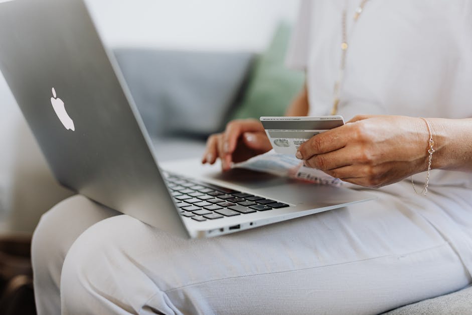 Person Using a Macbook and Holding a Credit Card · Free Stock Photo