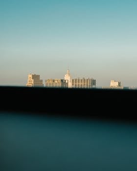 Picturesque view of tops of high buildings of modern city with skyscrapers against cloudless sky in daytime outside