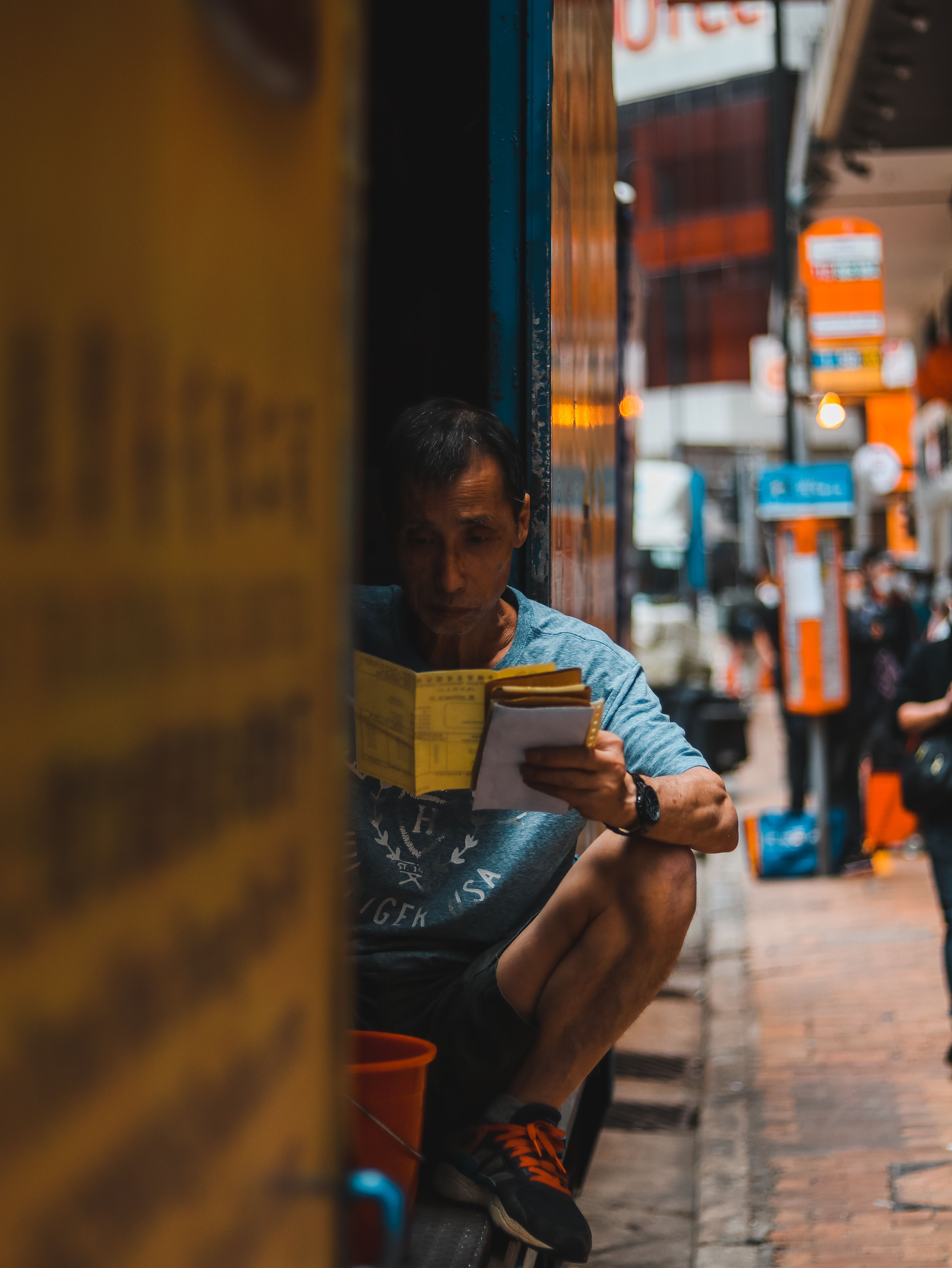 穿着休闲服的少数族裔成年男性工人坐在停在城市街道的送货卡车上阅读文件