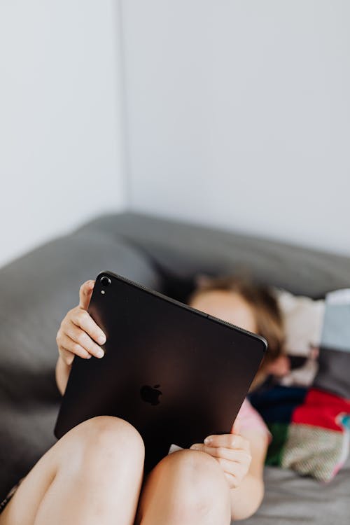 Person Lying on a Couch Holding Black Ipad 