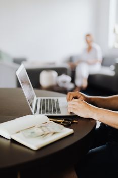 Casual home office setting with a man working on a laptop and another person in the background.
