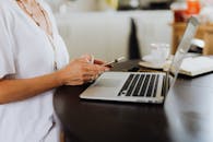 一名女子在家中的办公桌上，用智能手机和笔记本电脑参与技术活动