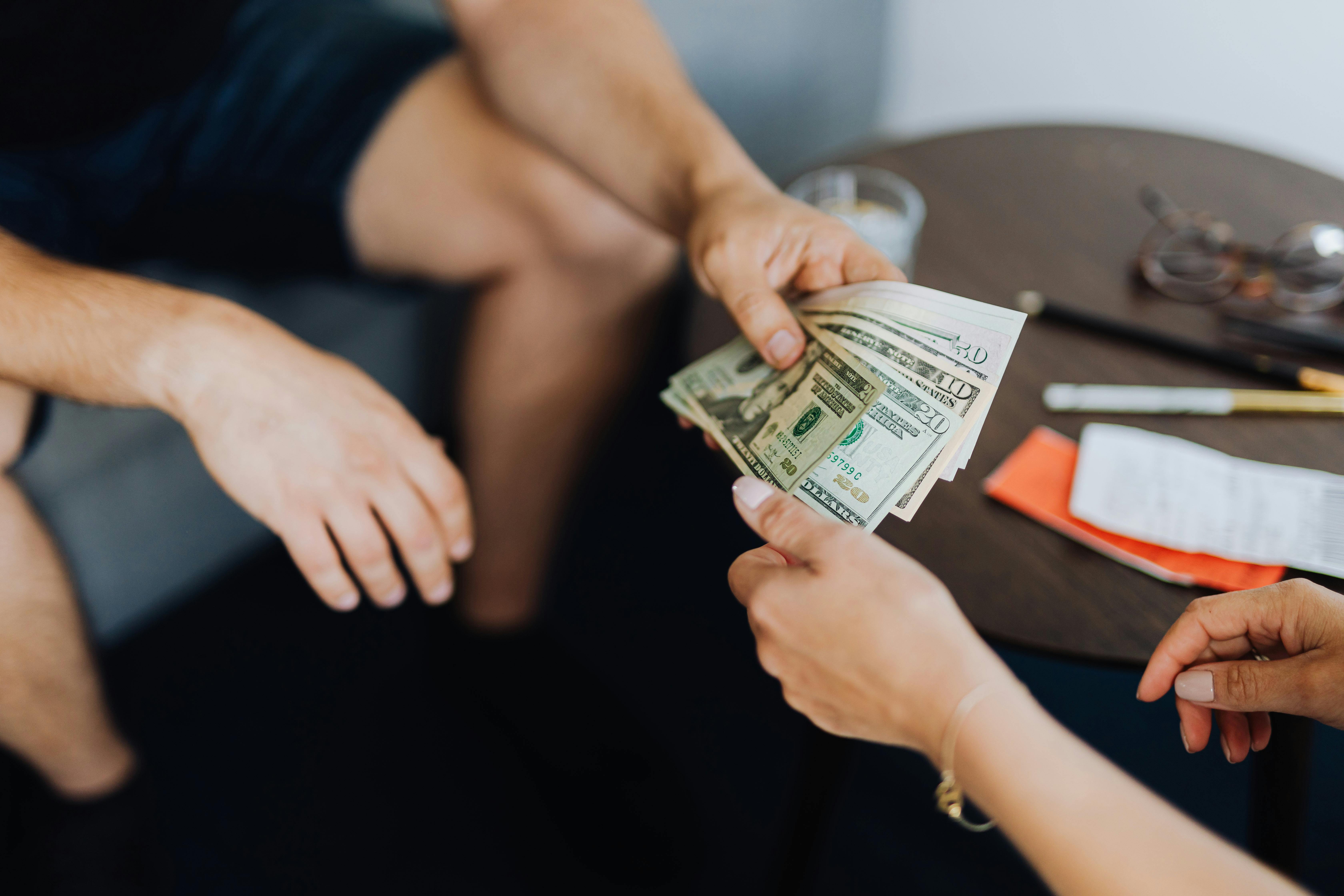A person giving money to another person. | Photo: Pexels