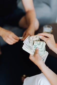 Hands exchanging cash in an indoor setting, representing financial transaction or budgeting.