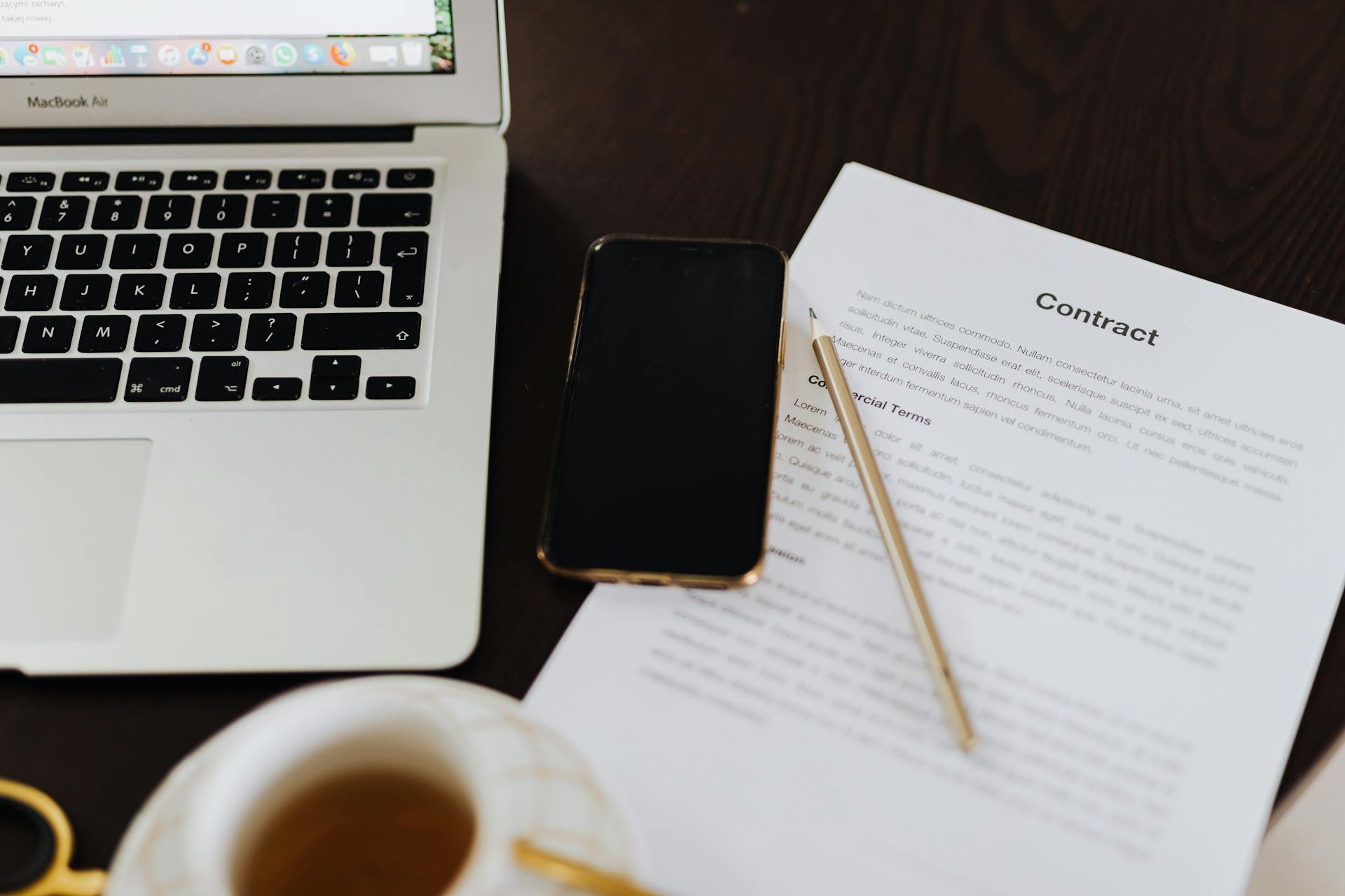 Laptop, Smartphone and a Contract Document Lying on the Desk