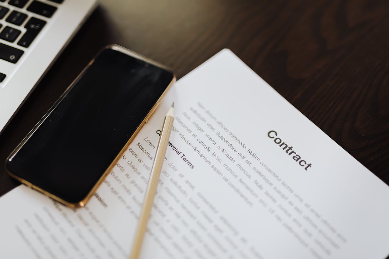 Primo piano di un contratto accanto a uno smartphone e un laptop