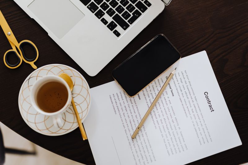 Legal contract signing with pen and laptop on wooden desk
