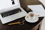 White Ceramic Cup on White Ceramic Saucer Beside Macbook Pro