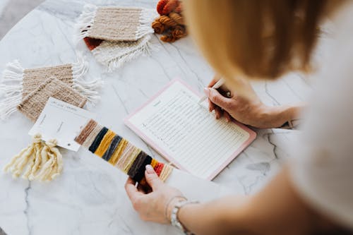 Woman Holding Fabrics and Writing in Planner