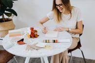 Woman with Yarn Samples Writing Notes in a Pad