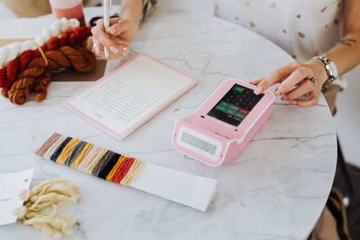 A creative professional calculating costs with yarn samples on a table.