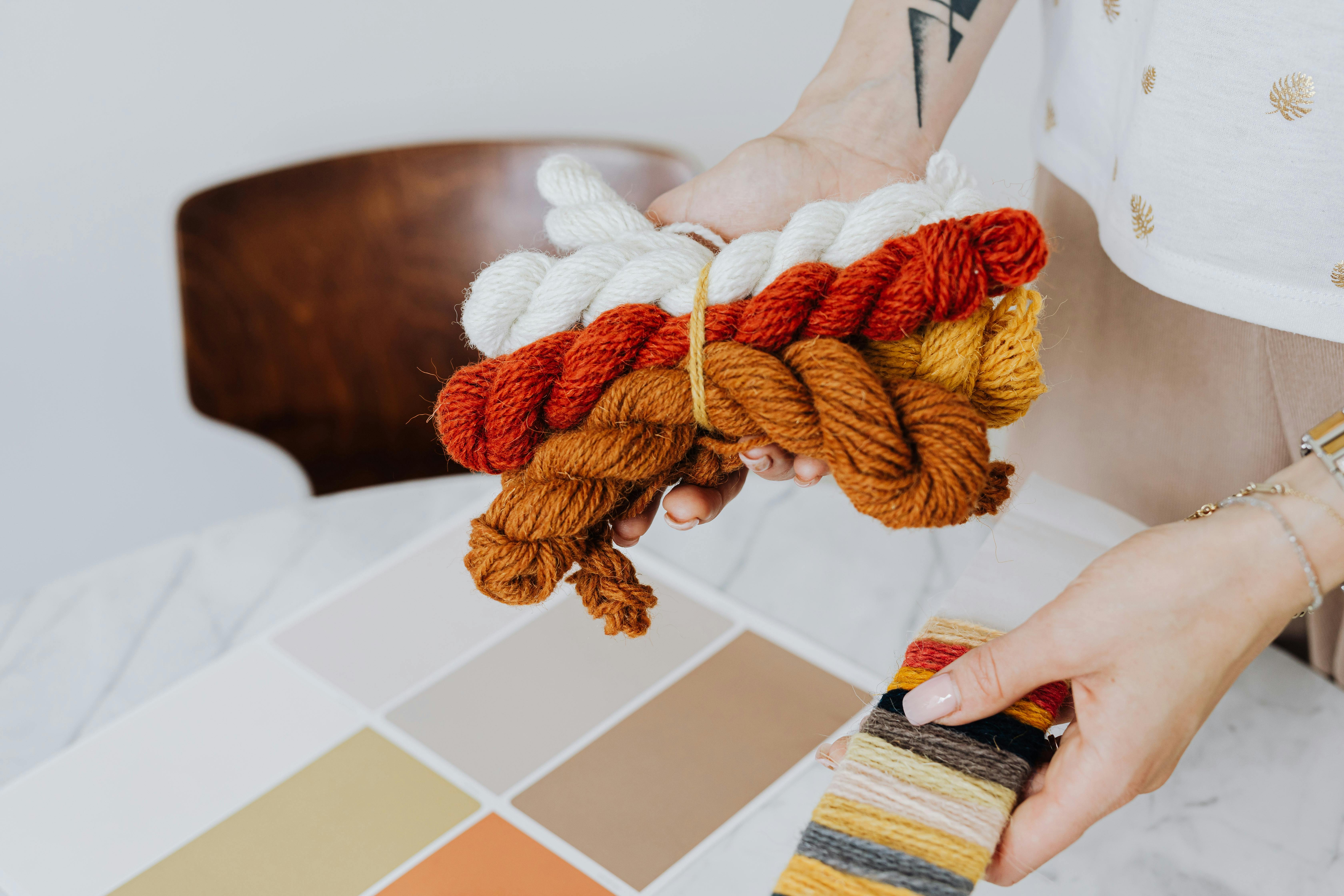 Hands holding colorful yarn and fabric swatches for creative design and craft projects related to best yarn types for crochet