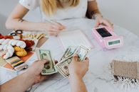 两个人正在桌旁用计算器和笔记本处理现金和预算