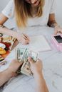 两个成年人在室内用现金、记事本和刷卡机整理财务